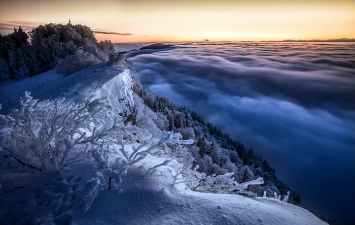 Winter mountain cliff above clouds at sunrise