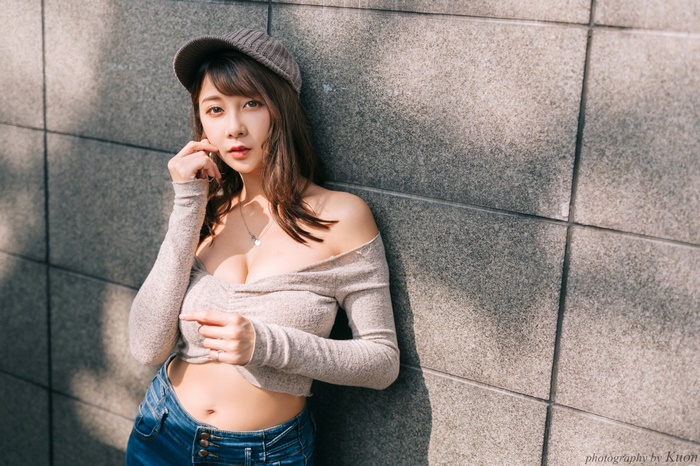 Asian woman wearing a grey off-the-shoulder top and jeans