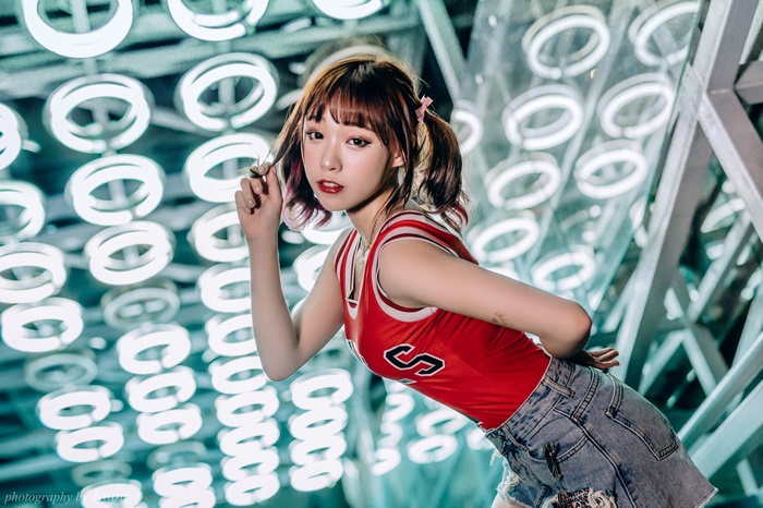 Asian woman with pigtails in red top and denim shorts