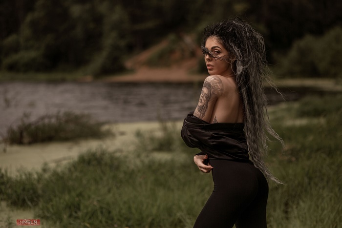 Woman with tattoos and long hair in black dress