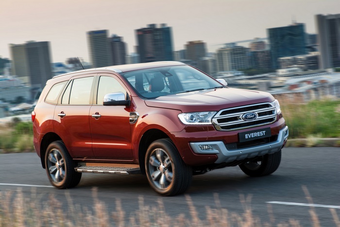 Red Ford Everest SUV driving on road with city skyline