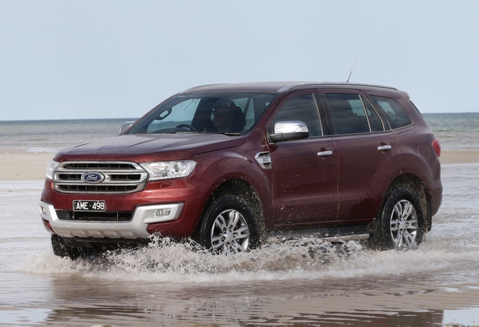 Red Ford Everest SUV driving through water on a beach