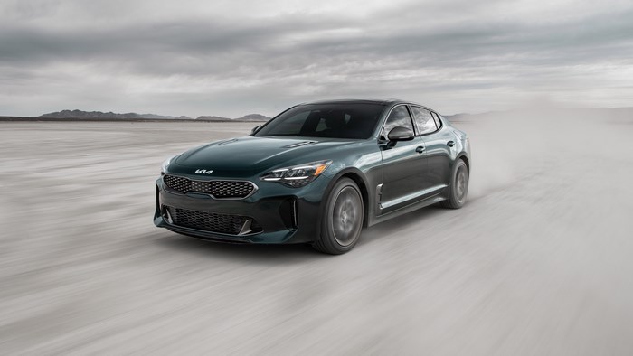 Green Kia Stinger driving on a dusty plain