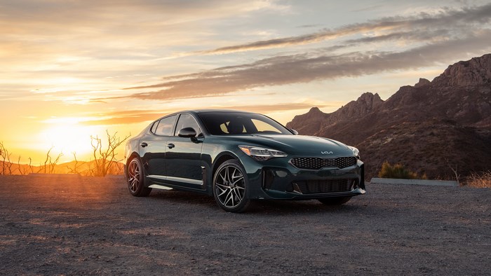 Green Kia Stinger parked at sunset with mountains