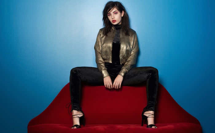 Charli XCX sitting on a red couch