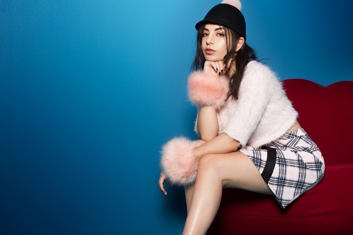 Charli XCX sitting on a red couch