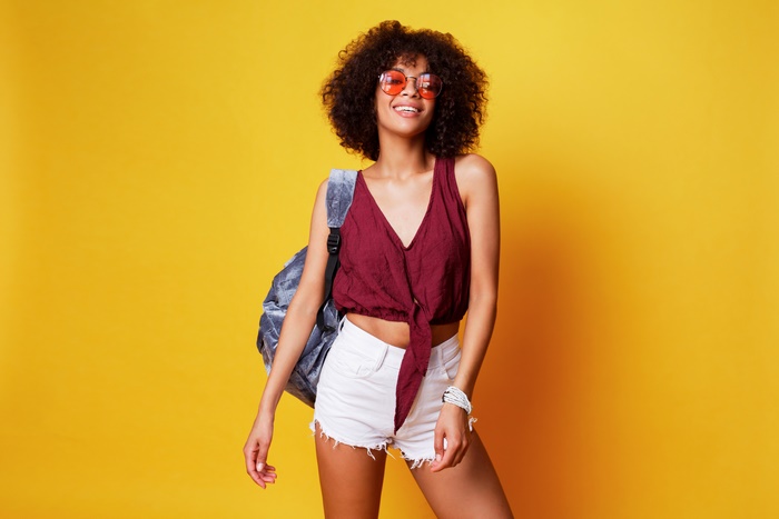 Woman with curly hair wearing sunglasses and shorts