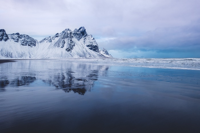 Snow-covered Vestrahorn Mountain reflecting on a wet beach in Iceland