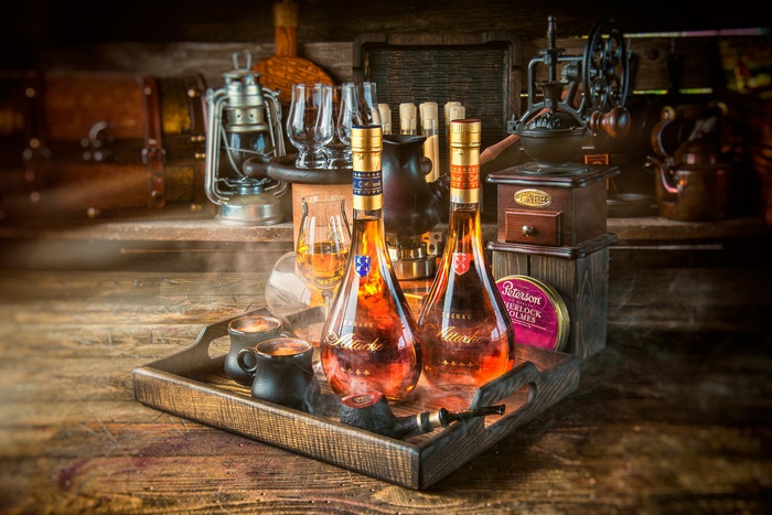 Two bottles of cognac on a tray with pipe and coffee grinder