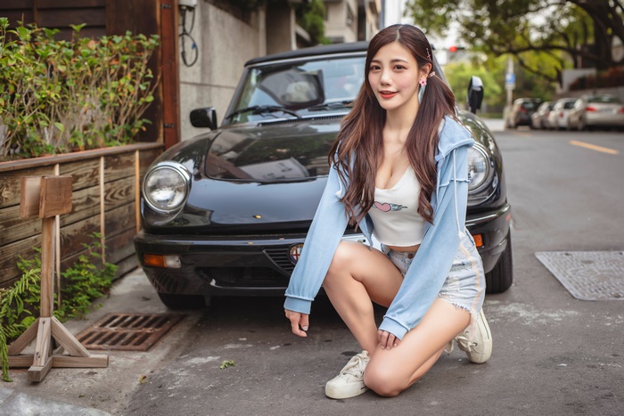Asian model with long hair posing by a car