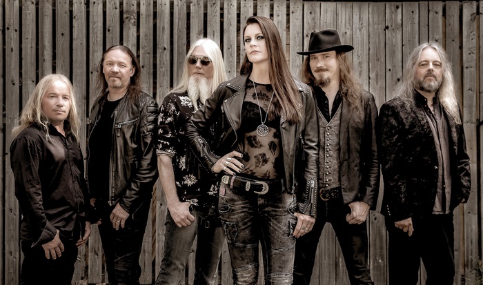 Nightwish band members posing in front of a wooden fence