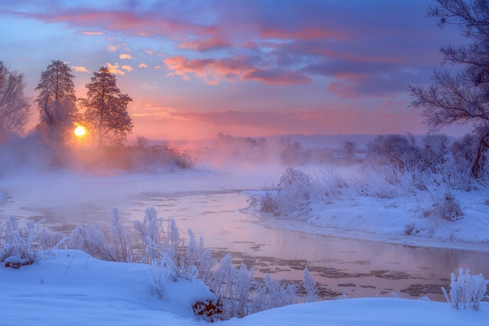 Sunrise over a misty river in a snowy landscape
