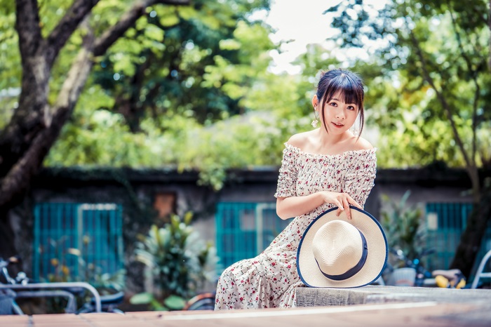 Asian woman with black hair wearing a floral dress and hat