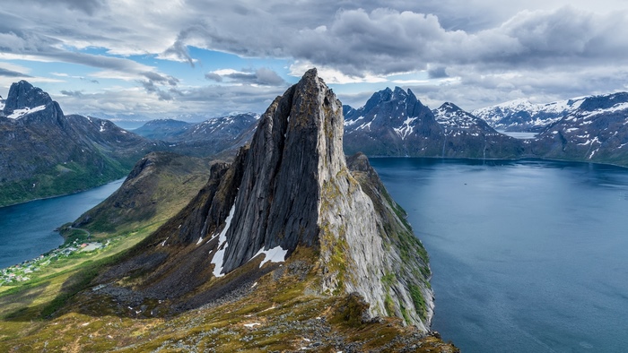 Jagged mountain peak overlooking a blue fjord and village