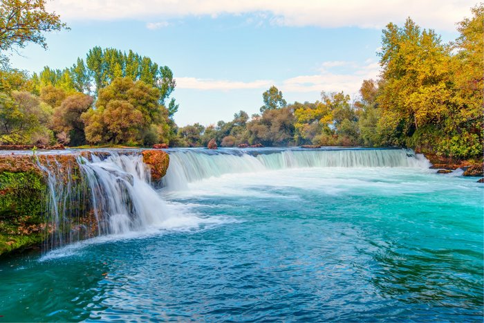 Waterfall with turquoise water and autumn trees