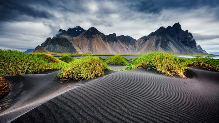 Black Sand Dunes and Mountains Under Cloudy Sky