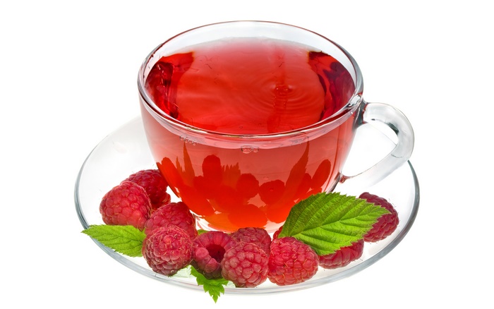 Raspberry tea in a glass cup with fresh raspberries