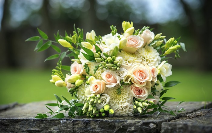 Wedding bouquet of roses and dahlias on stone