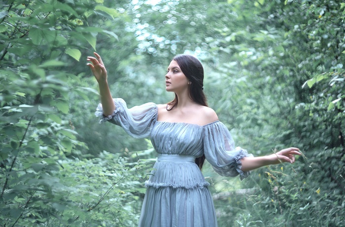 Elegant Woman in Blue Dress Among Greenery