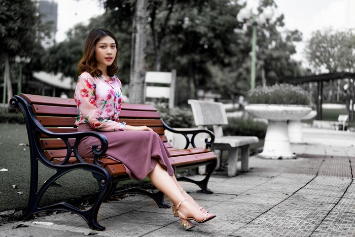 Asian woman sitting on a park bench