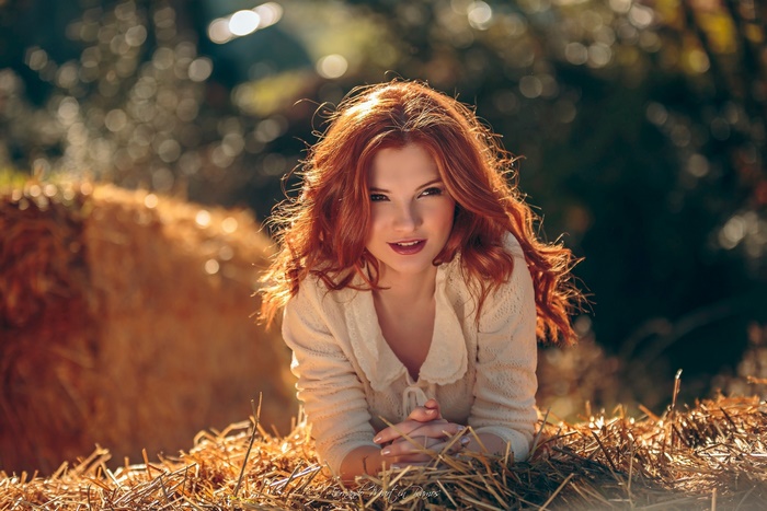 Redhead woman lying on hay bales