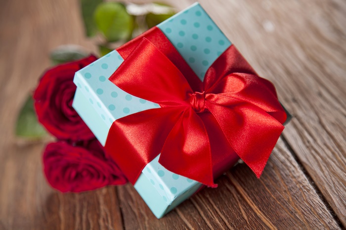 Gift box with red roses on wooden table