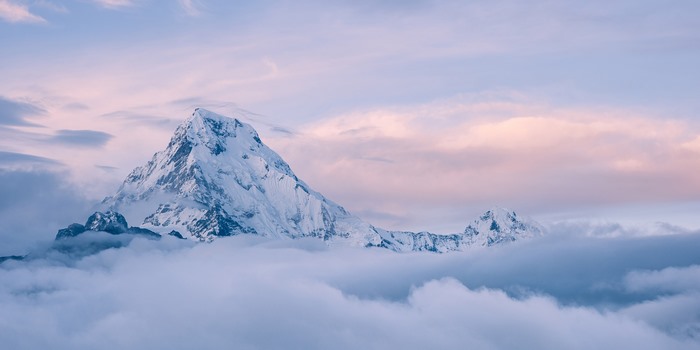 Snow-capped mountain peak above clouds at sunrise