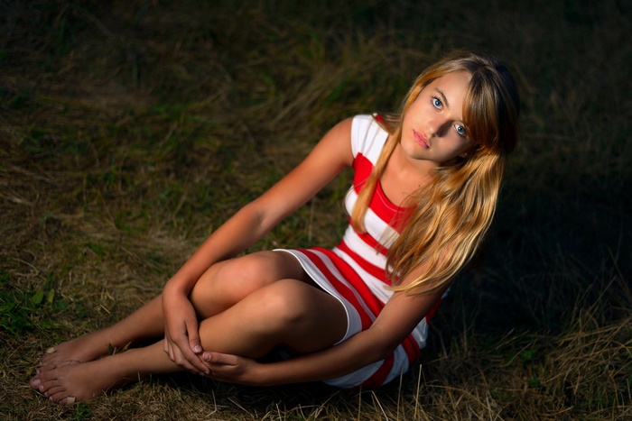 Young girl in a striped dress sitting on grass