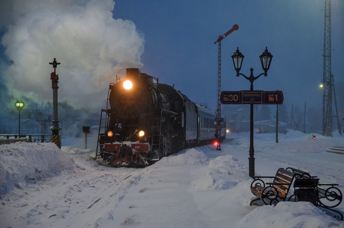 Steam train in a snowy station at night