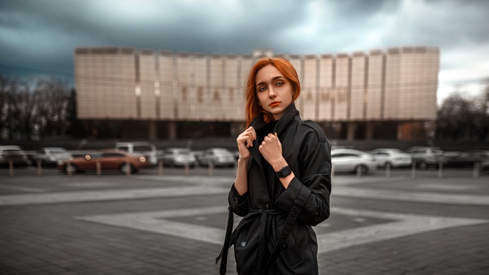 Redhead woman in trench coat in front of building