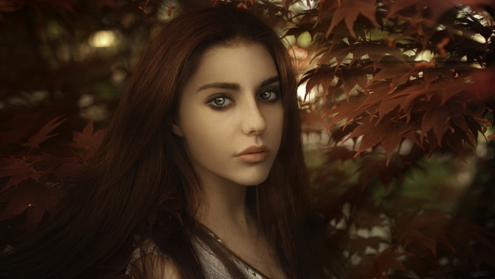 Woman with green eyes and red hair among red leaves