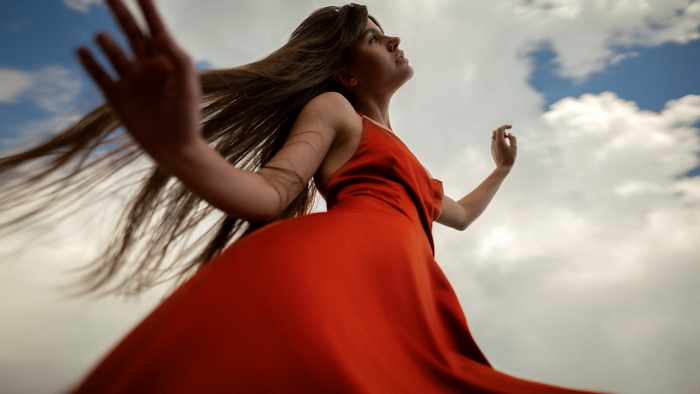 Woman in red dress against cloudy sky
