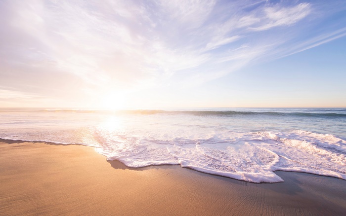 Ocean waves on a sandy beach at sunset