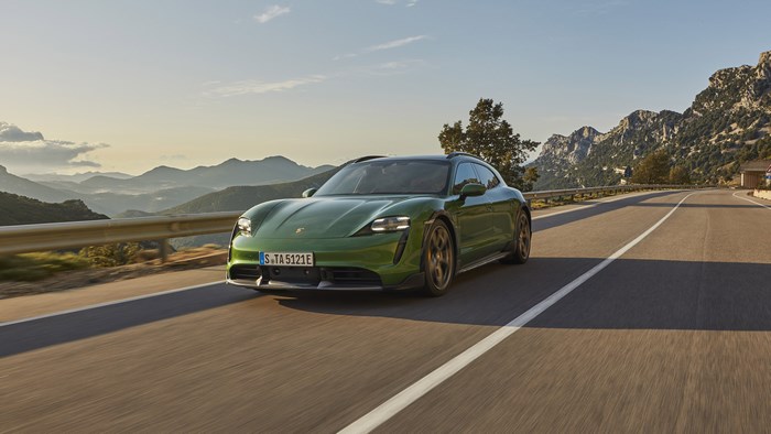 Green Porsche Taycan Turbo S driving on a mountain road