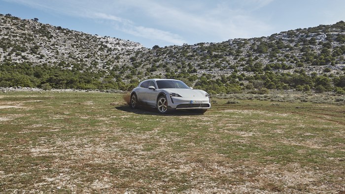 White Porsche Taycan 4S 4K parked in a rocky, grassy landscape