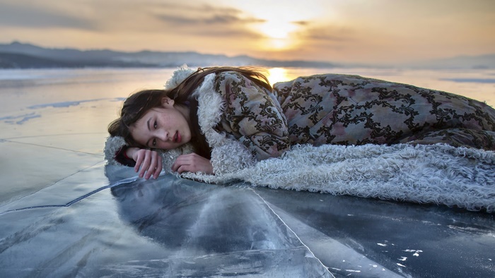 Young Asian woman lying on ice at sunset