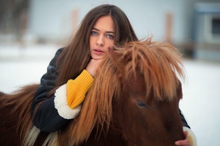 Woman with long brown hair and blue eyes with a pony