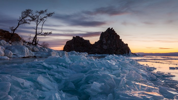Sunrise over frozen lake with ice formations and rock formations