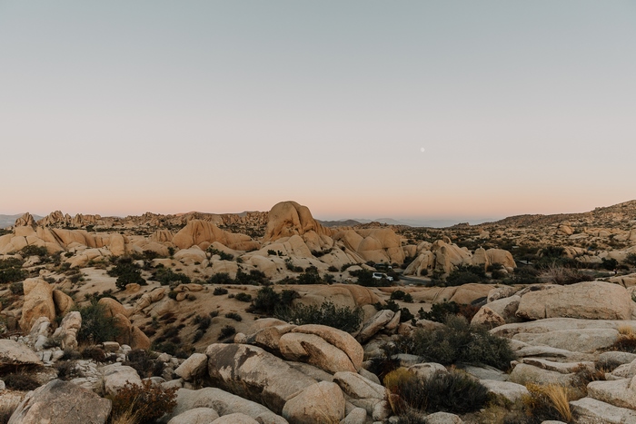 Desert landscape with rock formations and a faint moon