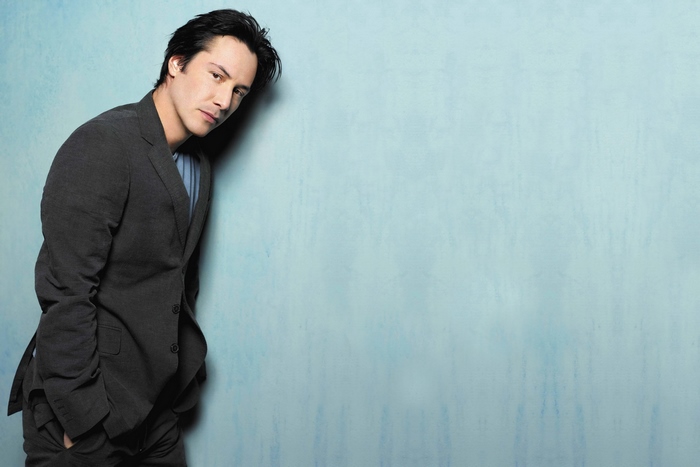 Keanu Reeves leaning against a blue wall
