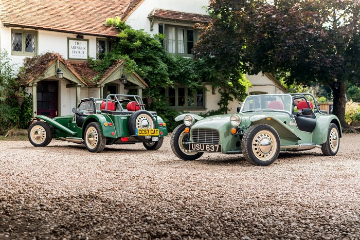 Two green Caterham Seven Sprint cars parked outside a building
