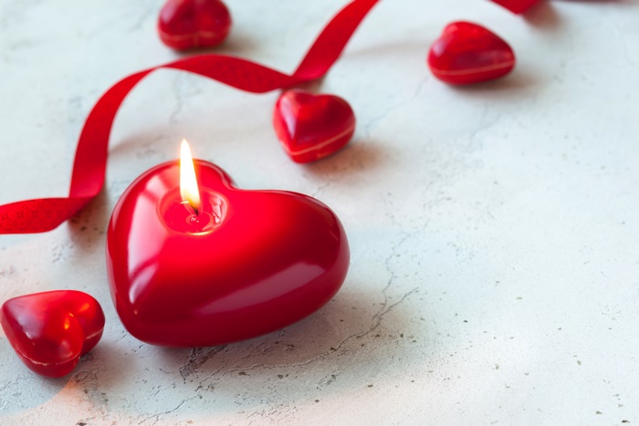 Heart-shaped candle with red ribbon and hearts