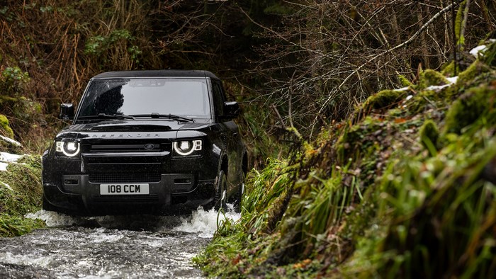 Black Land Rover Defender driving through water