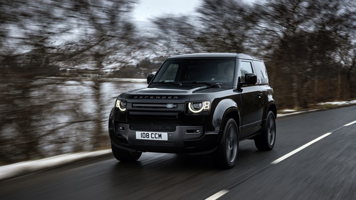 Black Land Rover Defender driving on a road