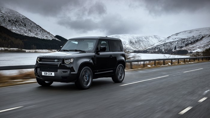 Black Land Rover Defender driving on a road