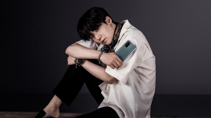 Suga from BTS holding a smartphone