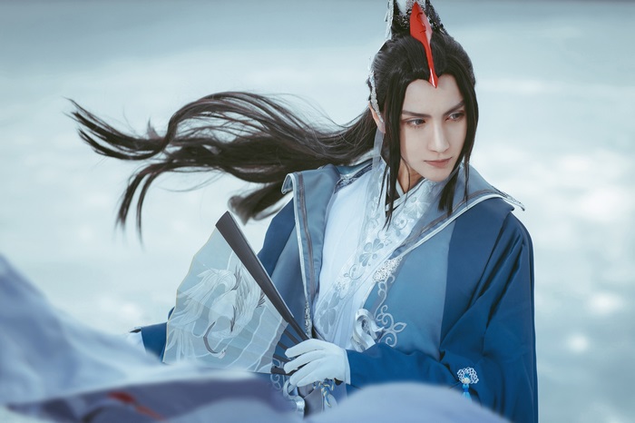 Man in blue traditional Asian cosplay holding a fan