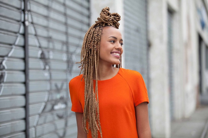 Woman with blonde box braids and orange dress