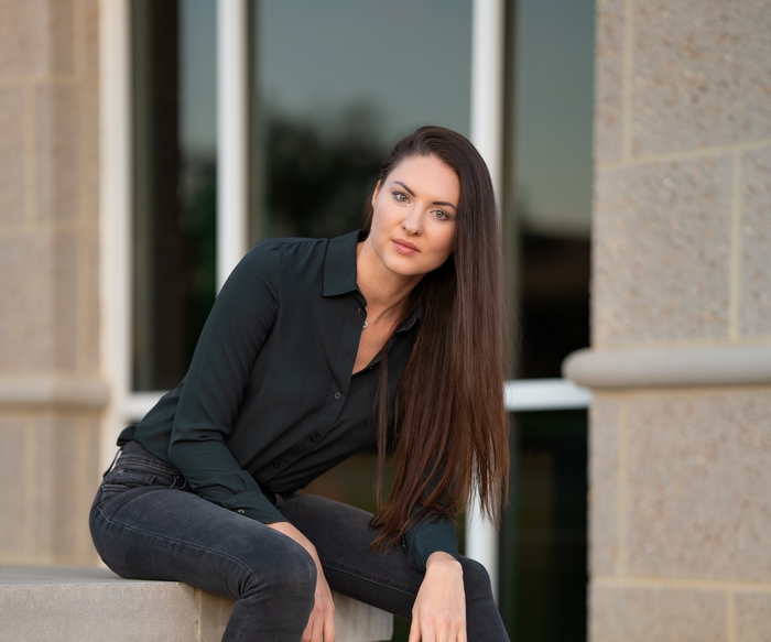Woman with long brown hair wearing a dark shirt and jeans