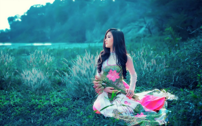 Woman in traditional dress holding lotus flowers